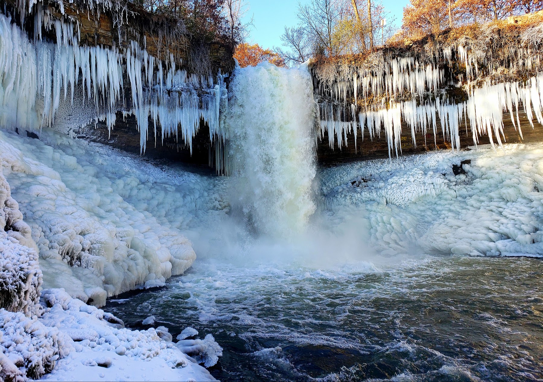Minnehaha Falls flows powerfully in spring, surrounded by the bare trees of early April.