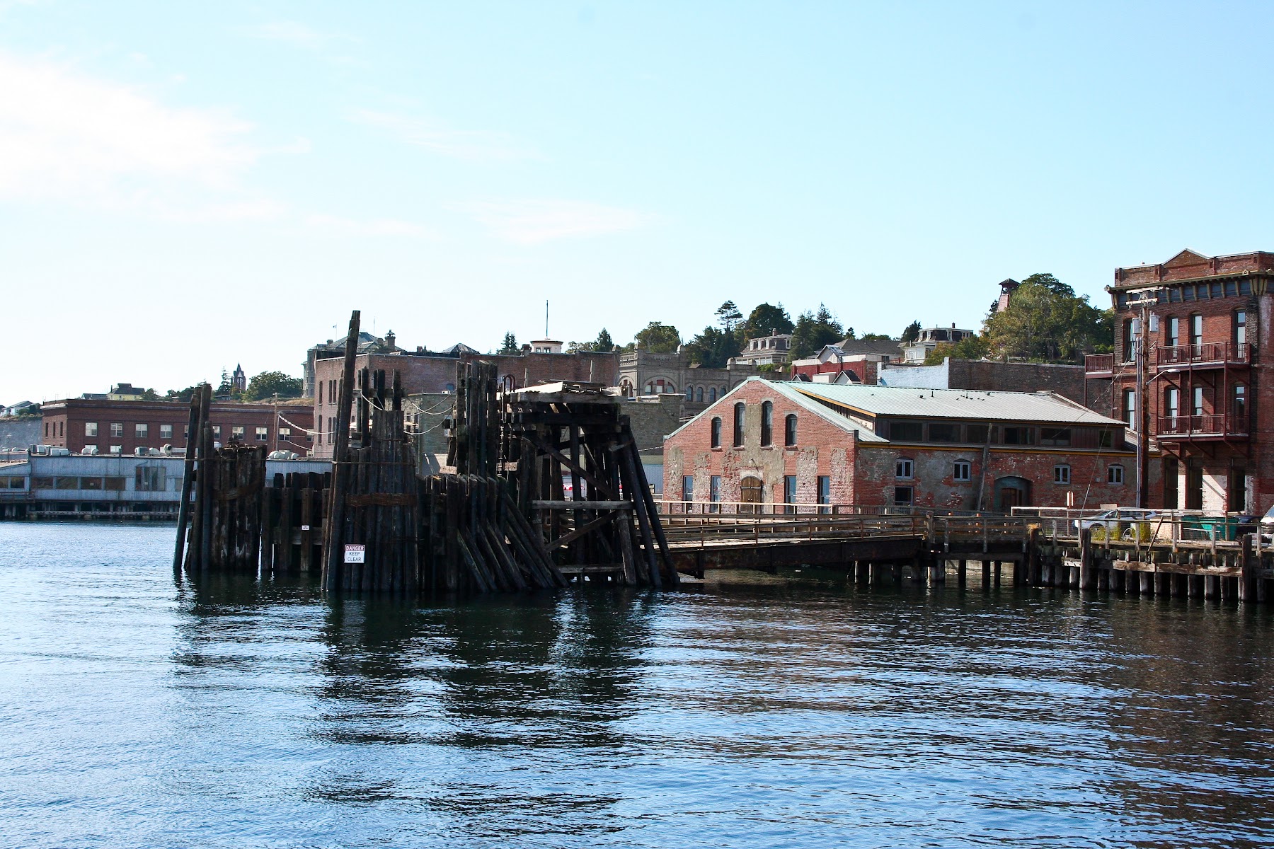 A peaceful marina in Port Townsend, Washington, with sailboats docked and forested hills in the background.