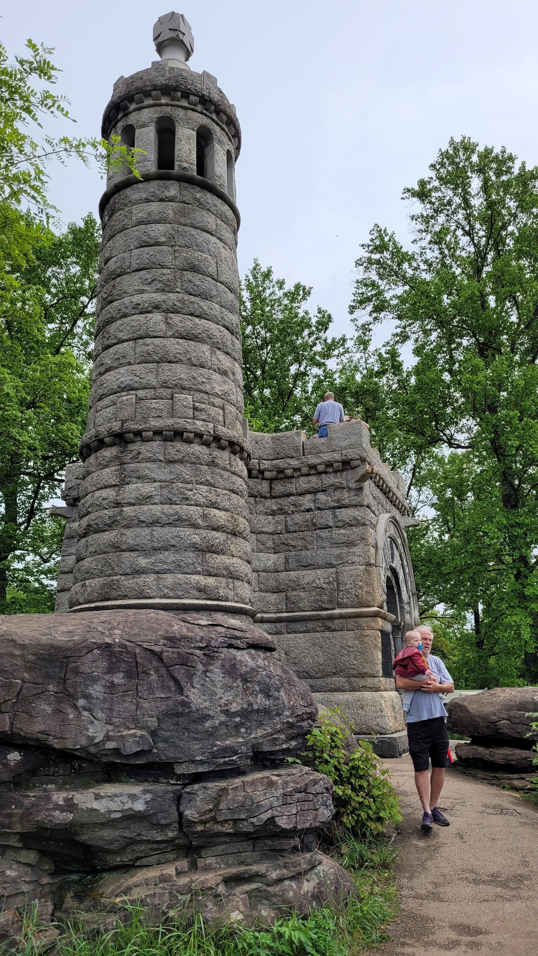 Lush green fields and historical cannons on the Gettysburg battlefield under a partly cloudy sky.